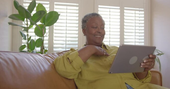 Senior Female Looking at Family pictures on Digital Tablet  at Home