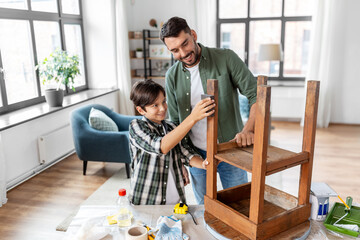 furniture renovation, diy and home improvement concept - father and son sanding old round wooden...
