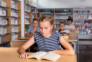 Fototapeta na wymiar Teenage schoolers reading and writing in college library