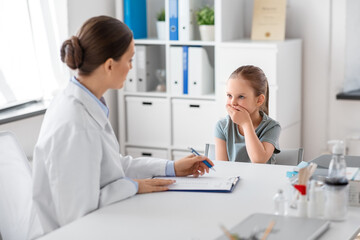Obraz premium medicine, healthcare and pediatry concept - female doctor or pediatrician with clipboard and coughing little girl patient on medical exam at clinic
