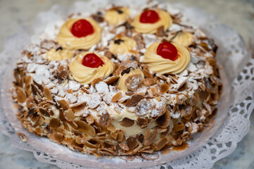 Cake with cream and roasted almond nuts on display in artisanal bakery in San Sebastian city, Basque Country, Spain