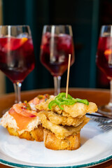 Food and drink in bars of Basque Country and Navarre, pinchos or pinxtos, slices of bread with different toppings fastened with skewers served with glasses of cold sangria wine, San Sebastian, Spain