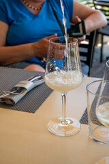 Drinking of txakoli or chacolí slightly sparkling very dry white wine produced in Spanish Basque Country, served in restaurant in Getaria, Spain