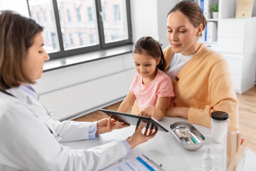 Obraz premium medicine, healthcare and pediatry concept - mother with little daughter and doctor showing tablet pc computer at clinic