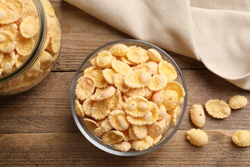 Bowl with tasty corn flakes on wooden table, flat lay