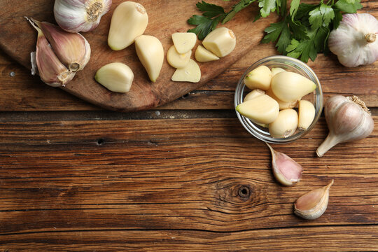 Flat lay composition with fresh garlic bulbs and cloves on wooden table, space for text. Organic product