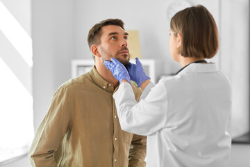 medicine, healthcare and people concept - female doctor checking lymph nodes of man patient at...