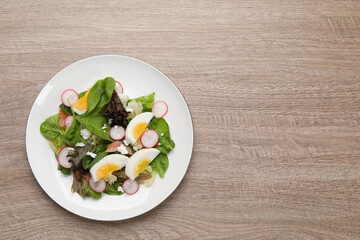 Delicious salad with boiled egg, radish and cheese on wooden table, top view. Space for text