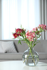 Vase with beautiful alstroemeria flowers on table in living room, space for text. Stylish element of interior design