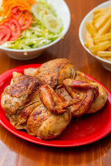 Grilled chicken with french fries on a wooden table.
