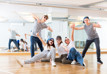 Obraz premium Group of teenagers in casual clothes training hip-hop in class, posing and having fun