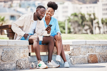 Fototapeta na wymiar Black couple, love and phone while browsing social media, internet or watching a video while sitting on a park bench. Happy man and woman on a romantic date, trip or summer holiday to relax together