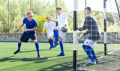 Youthful football players challenging for ball in goalmouth zone