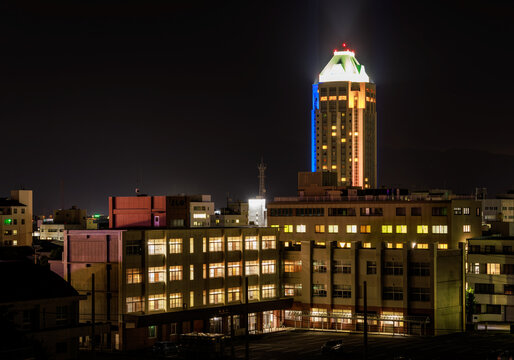 High Rise Building Towers Over Lit Multi-story School At Night