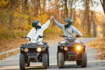 Man and woman driving quad bikes in autumn forest