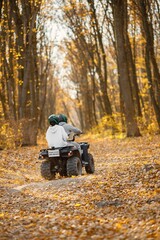 Man and woman driving quad bike in autumn forest