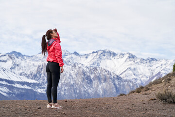 Naklejka premium young woman standing in red jacket, looking at snowy mountains in the middle of the Andes Mountains of Chile