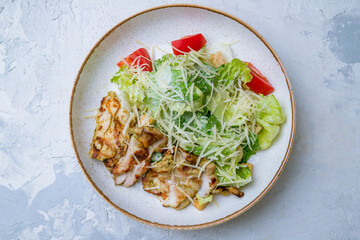 Salad caesar with chicken on plate on white concrete table top view