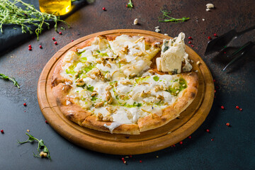 Pizza with pears and Gorgonzola cheese on the board on dark table