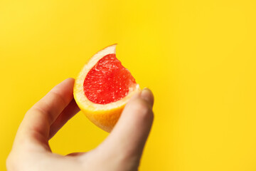 Defocus female hand holding piece of a red grapefruit. Healthy food concept.  Fresh orange juice. Vegan, vegetarian concept. Banner with copy space. Out of focus