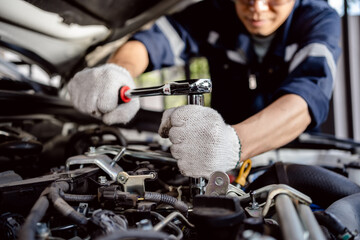 Auto mechanic repairman using a socket wrench working engine repair in the garage, change spare part, check the mileage of the car, checking and maintenance service concept.