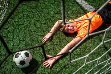Young soccer player reaching for the ball but failing to prevent a goal from being scored
