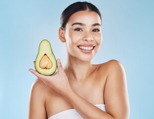 Skincare, health and avocado with a woman portrait on studio blue background and mockup. Young model with healthy fruit nutrition for face, skin care ingredients and clean, perfect or natural results