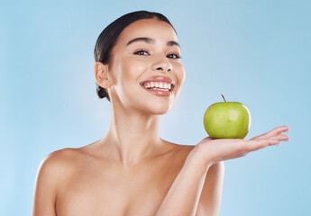 Health, food and apple diet with happy woman holding fruit against blue background. Portrait of a young female excited by weight loss and nutrition, showing benefits of healthy, balance lifestyle