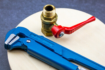 Plumbing wrench and pipe faucet fixture. Connector on a wooden table. Change of plumbing fixtures.