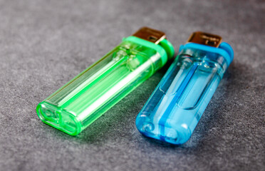 Blue and green gas lighters on the table. Pocket plastic lighters used by smokers.