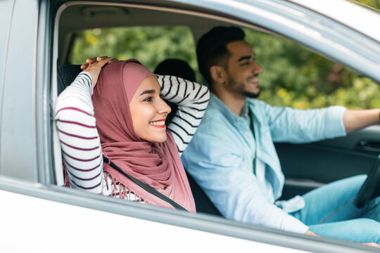 Glad Cheerful Millennial Middle Eastern, Woman In Hijab Enjoy Trip, Husband At Steering Wheel Driving At Road