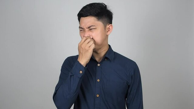 Asian man feels very smell gesture close his nose white background