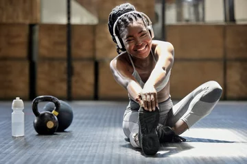 Fotobehang Fitness Portrait of woman stretching with music at gym, audio podcast for workout motivation and happy about fitness training on floor at health club. African athlete or sports person doing exercise