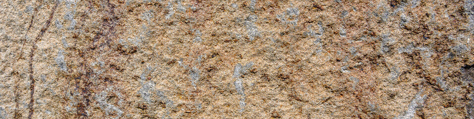 Closeup of an orange rock with tan patches, patterns and textures in nature as a background

