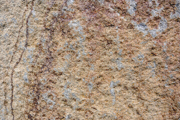 Closeup of an orange rock with tan patches, patterns and textures in nature as a background
