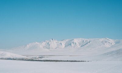 Fototapeta na wymiar Village among snowy mountains and fields.
