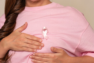 Woman doing breast palpation with pink shirt and with pink ribbon for breast cancer awareness day
