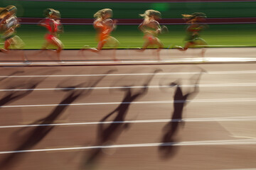 陸上競技でトラックを走る選手と影