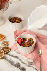 Bowl of granola and jar of milk pouring