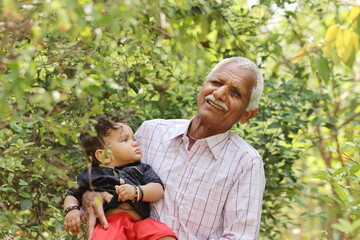Indian Hindu grandfather raised little grand son in the dock in the garden