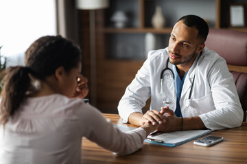 Arab man doctor having conversation with upset black woman patient