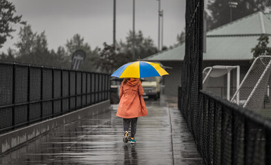 A young woman walking with umbrella on rainy day. Street photo of a woman with colorful umbrella