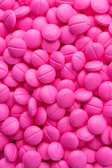pile of pink round pills or tablets, medical drugs taken straight from above, full frame background close-up