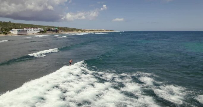 Aerial view following a surfer riding a wave and falling in the sea, on the coast of Isabela, Puerto Rico, USA