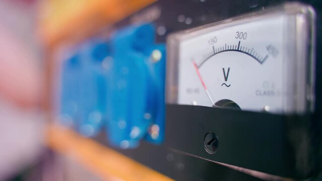 Gas generator voltmeter during engine start close-up with a blurred background. Starting a gasoline electric generator with a manual starter in the background. Unstable power supply.