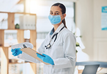 Portrait of a doctor with paper and face mask doing medical paperwork during covid pandemic. Healthcare worker reading coronavirus results on a clipboard of hospital patient while standing in clinic.