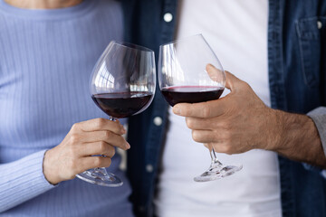 Unrecognizable couple drinking red wine at kitchen, closeup
