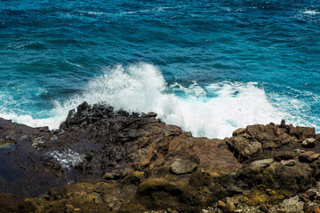 Offshore mountain rock and big wave hitting the shore