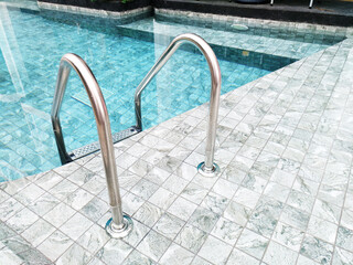 Grab bars ladder in the blue swimming pool