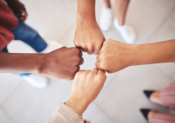 Hands, teamwork and collaboration with a team of business people joining their fists in a circle in...